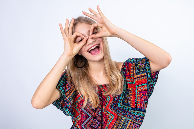 Alegre joven mujer rubia mirando a través de sus dedos