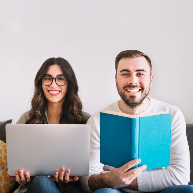 Alegre joven pareja con portátil y libro