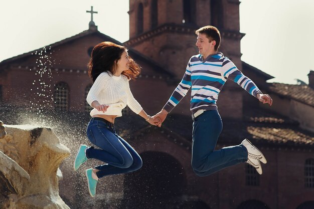 Alegre joven pareja salta antes de la fuente en algún lugar de Roma