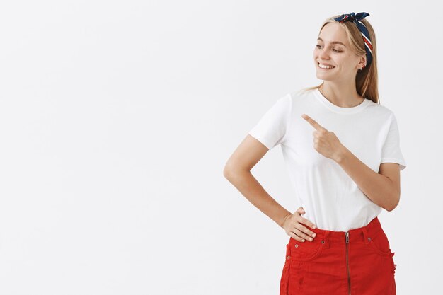 Alegre joven rubia sonriente posando contra la pared blanca