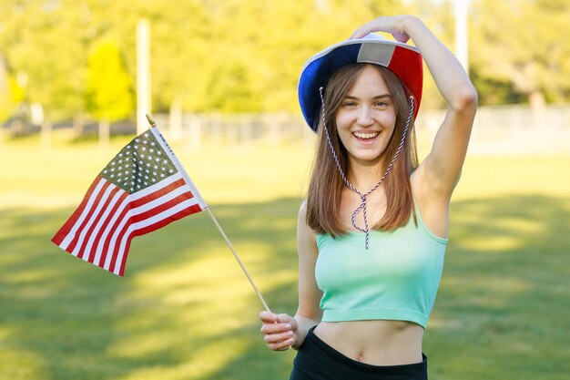 Alegre joven sosteniendo la bandera y sonriendo a la cámara