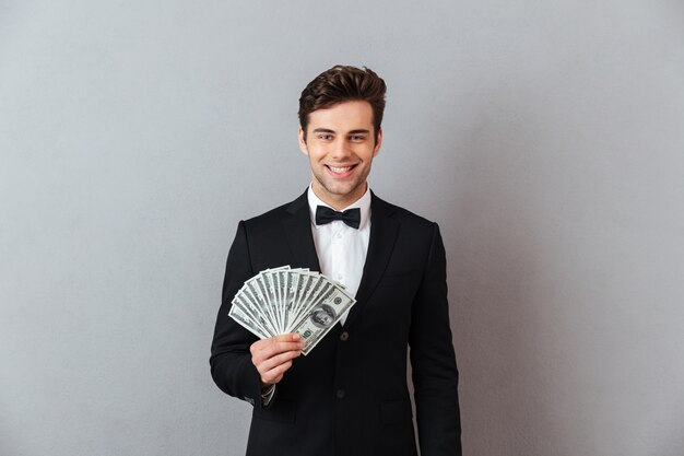 Alegre joven en traje oficial con dinero.