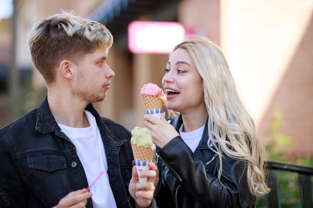 Alegre jovencita comiendo helado con su novio Foto de alta calidad