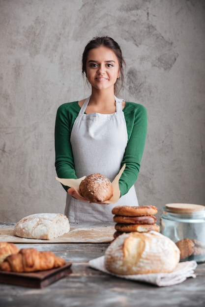 Alegre lady baker de pie y sosteniendo pan