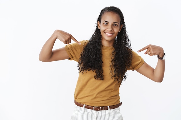 Foto gratuita alegre linda chica afroamericana apuntando a sí misma