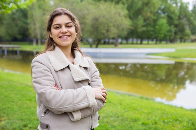 Alegre linda chica universitaria posando en el parque