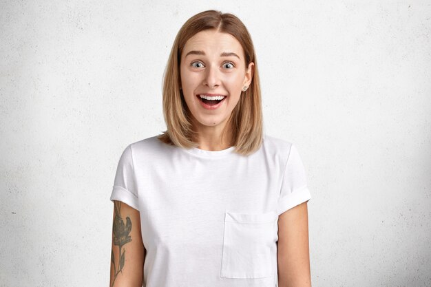 Alegre mujer adorable positiva con expresión emocionada, recibe sorpresa inesperada de un amigo vestido con ropa casual