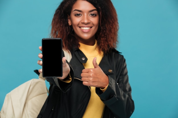 Alegre mujer africana estudiante mostrando la pantalla del teléfono móvil