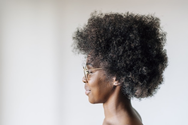 Alegre mujer afroamericana posando contra una pared blanca