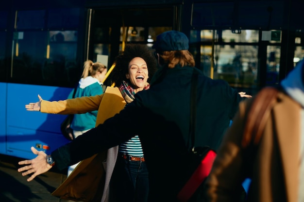 Foto gratuita alegre mujer afroamericana reunida con su novio en la estación de autobuses