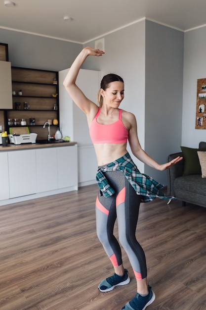 Alegre mujer bailando en medio de la cocina disfrutando de ella y la vida