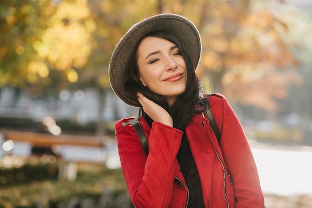 Alegre mujer blanca en traje rojo disfrutando del otoño