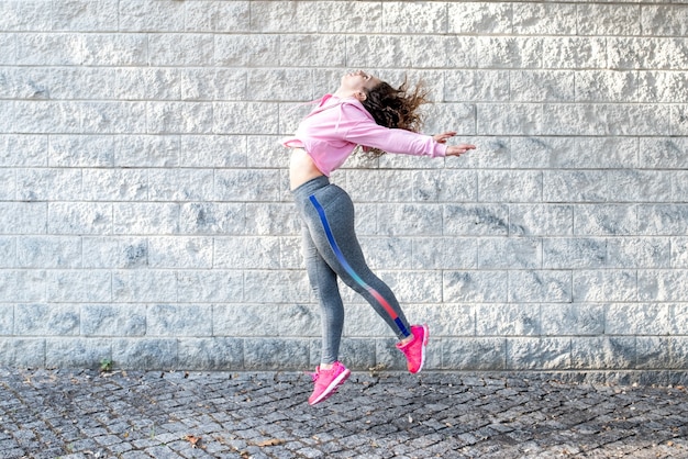 Alegre mujer deportiva saltando en la calle