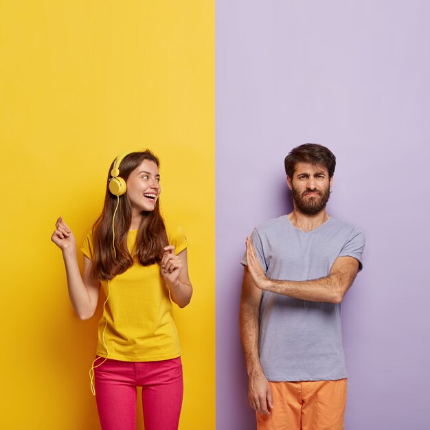 Foto gratuita alegre mujer despreocupada en camiseta amarilla casual, pantalón rosa, escucha música en auriculares modernos