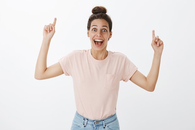 Alegre mujer elegante joven feliz posando contra la pared blanca