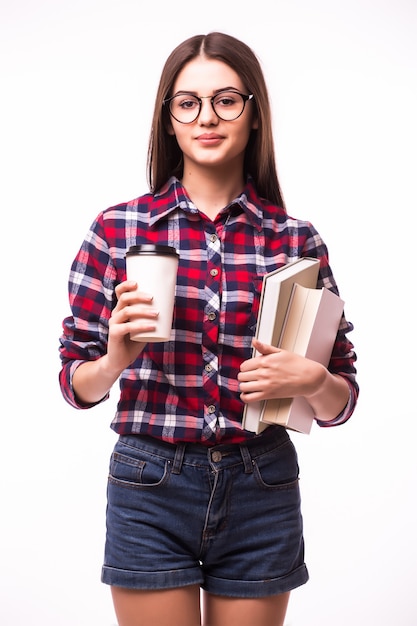 Alegre mujer feliz con una gran sonrisa, lleva café para llevar y libro rojo, feliz de terminar de estudiar