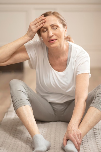 Alegre mujer de mediana edad relajante después de hacer ejercicios de yoga