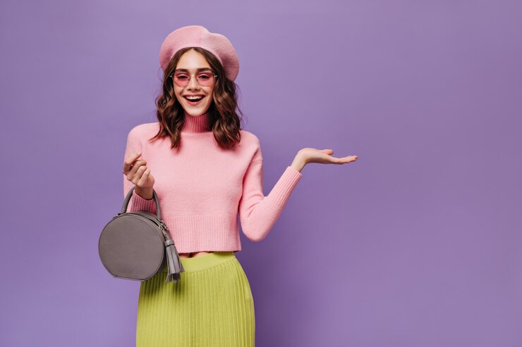 Foto gratuito alegre mujer parisina en boina y gafas de sol apunta al lugar para el texto en la pared púrpura
