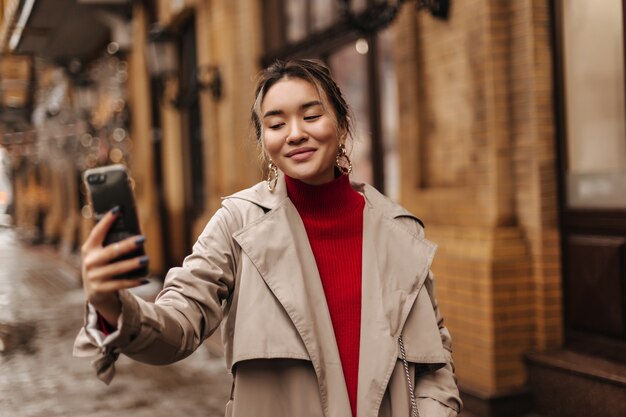 Alegre mujer rubia hace selfie caminando en ciudad europea