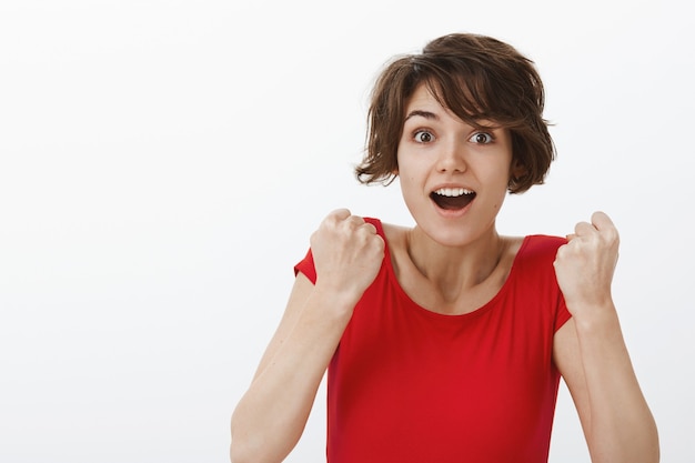 Foto gratuita alegre mujer triunfante que parece esperanzada, ganando y logrando la meta, regocijándose