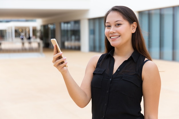 Foto gratuita alegre niña estudiante sonriente usando la aplicación en línea