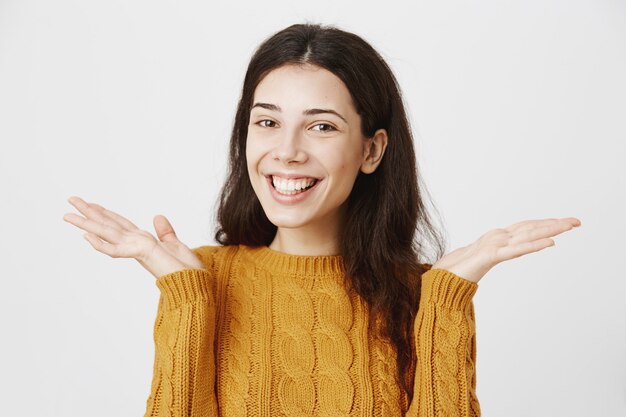 Alegre niña morena sonriente extendió las manos hacia los lados, termine los exámenes fácilmente, no se preocupe