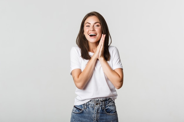 Foto gratuita alegre niña morena sonriente frotar las manos y esperar deleite.