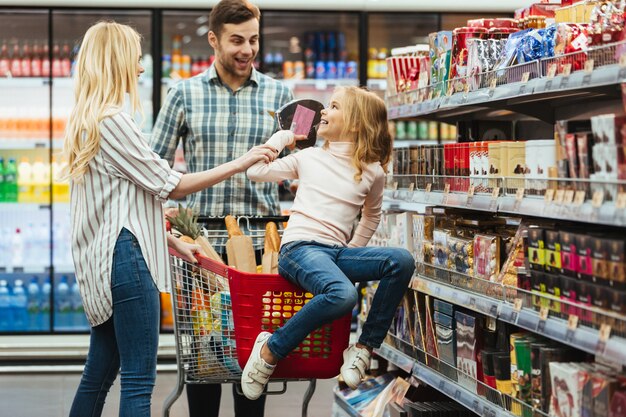 Alegre niña sentada en un carrito de compras