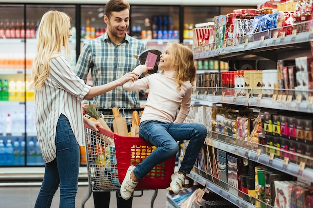 Alegre niña sentada en un carrito de compras