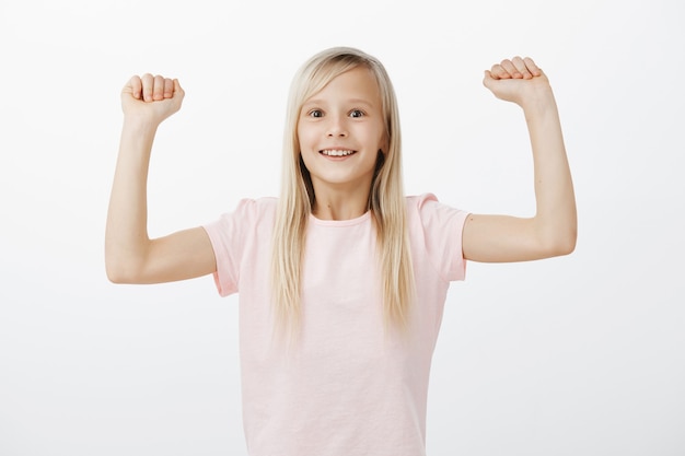 Alegre niña sonriente levanta las manos, ganando y triunfando