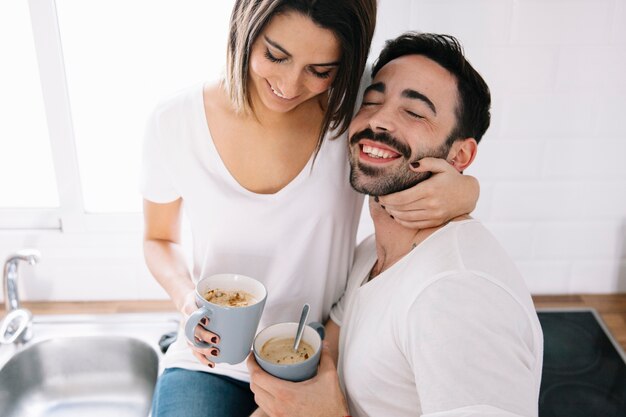 Alegre pareja abrazándose y tomando café