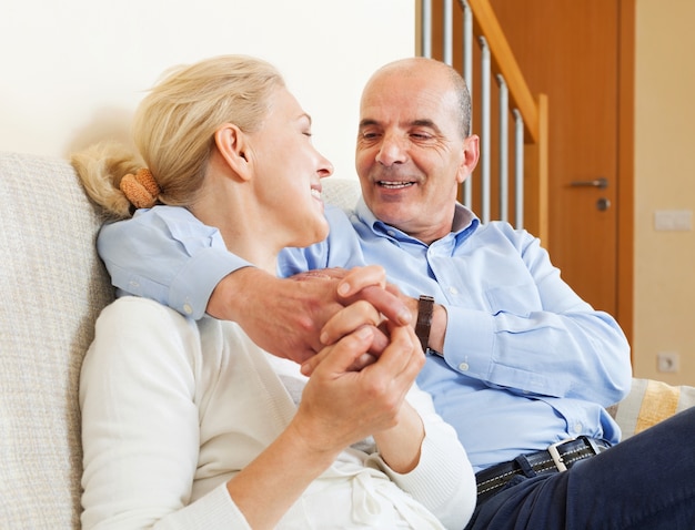 alegre pareja de ancianos junto en el sofá en el interior del hogar