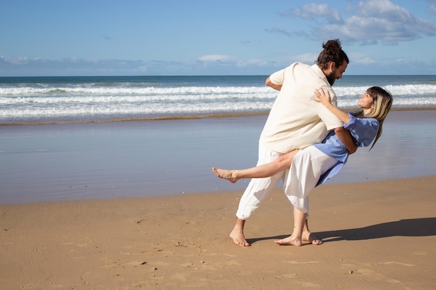 Alegre pareja caucásica bailando descalzo en la playa