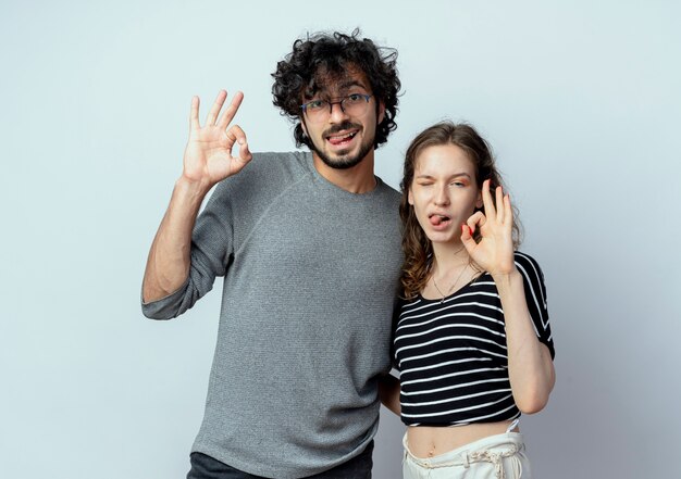 alegre, pareja joven, hombre y mujer, actuación, ok, señal, sacando lenguas, encima, pared blanca