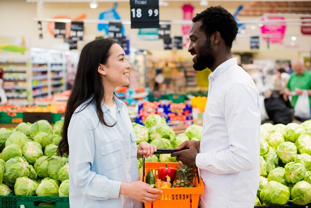 Alegre pareja multiétnica en tienda de comestibles