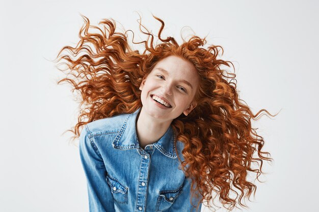 alegre pelirroja mujer con cabello rizado volando sonriendo riendo.