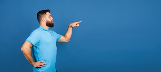 Alegre. Retrato de hombre hermoso caucásico aislado en la pared azul con copyspace. Modelo masculino con barba.