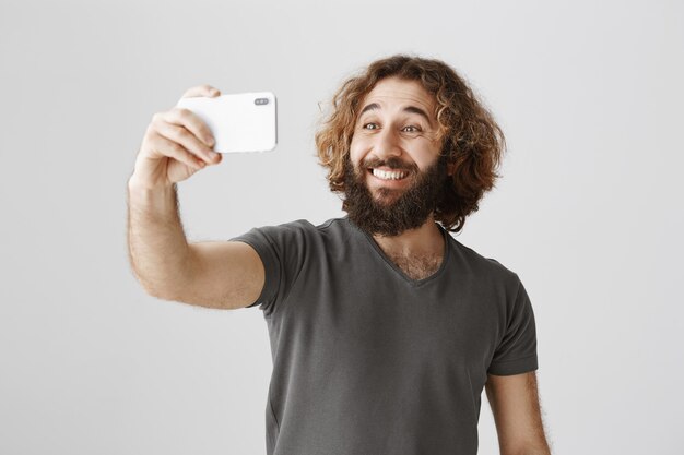 Alegre sonriente hombre del Medio Oriente tomando selfie con smartphone