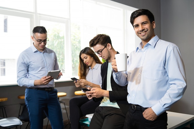 Foto gratuita alegre trabajador disfrutando de un coffee break sin internet móvil.