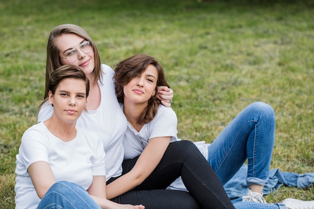 Alegres amigas sentadas en el parque abrazando