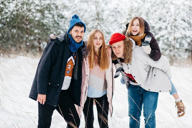 Alegres amigos de pie en el bosque de invierno