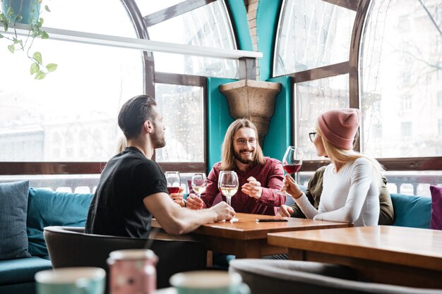 Alegres amigos sentados en la cafetería y beber alcohol.