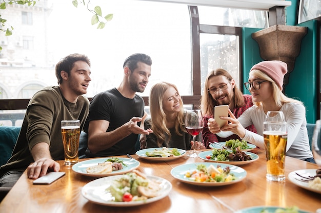 Alegres amigos sentados en la cafetería hablando entre sí.