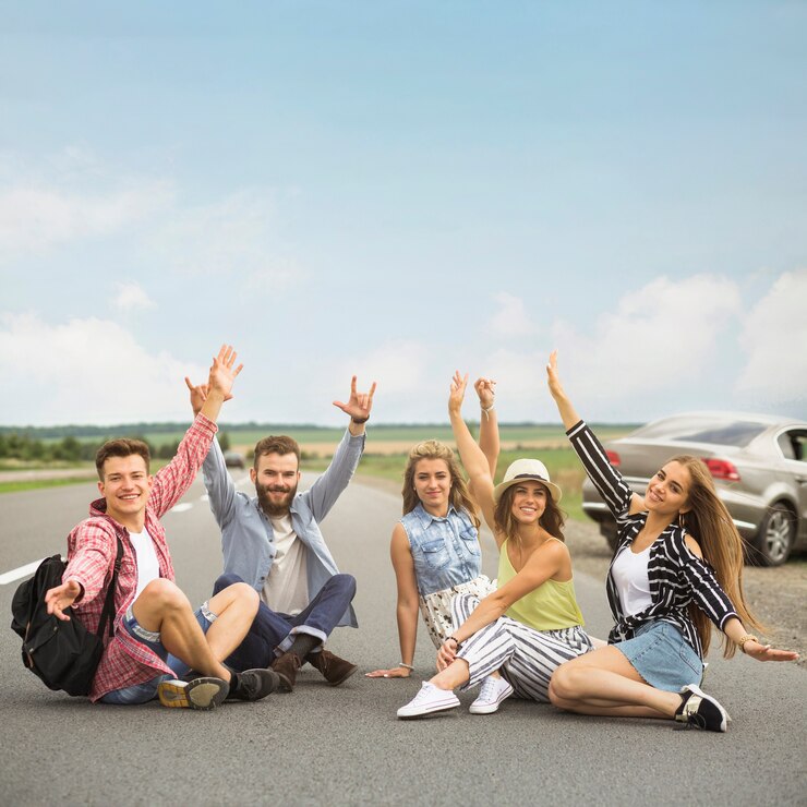 Foto gratuito alegres amigos sentados en la carretera levantando sus manos gesticulando