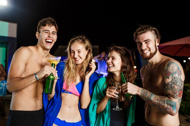 Alegres amigos sonriendo, regocijándose, descansando en la fiesta junto a la piscina