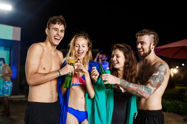 Alegres amigos sonriendo, regocijándose, descansando en la fiesta junto a la piscina