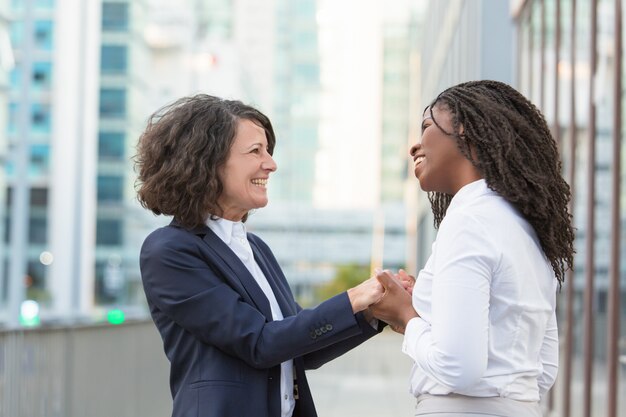 Alegres colegas femeninas felices que comparten buenas noticias