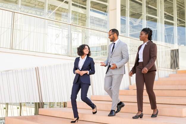 Alegres colegas de negocios caminando en el edificio de oficinas