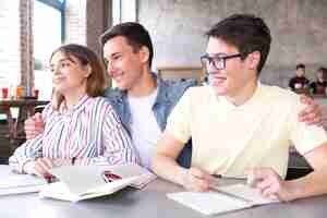 Foto gratuita alegres estudiantes en mesa en el interior