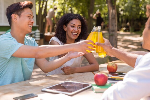 Alegres jóvenes amigos multiétnicos estudiantes al aire libre beber jugo.